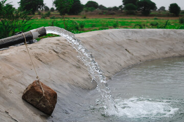 Water from a well filled a pond for irrigation,Irrigation of fields using pump wells with the technique of pumping water from the ground to flow into the fields,farming concept,selective focus