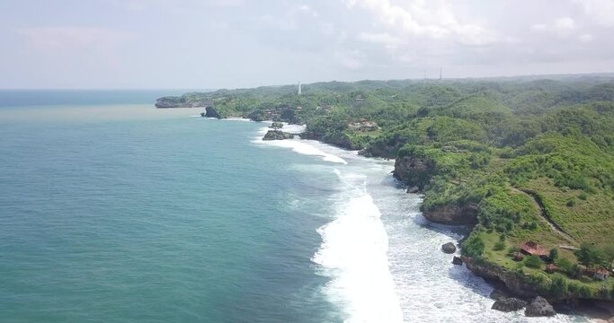 coastline on the south beach of java island in the morning, yogyakarta, Indonesia. beach on the edge of a cliff. drone shot of sea wave in Indonesia. sea ​​foam 4K videos.