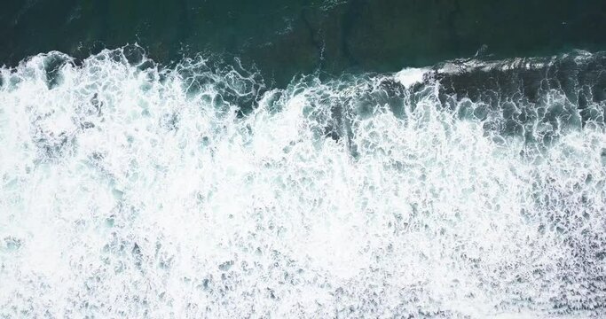 coastline on the south beach of java island in the morning, yogyakarta, Indonesia. beach on the edge of a cliff. drone shot of sea wave in Pantai Selatan, Indonesia. sea ​​foam 4K videos.