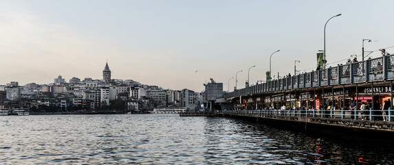 Istanbul, Turkey - April 2022: Medieval Galata Tower and Galata bridge in the evening