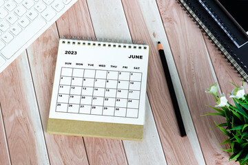 White June 2023 calendar on wooden desk . Flat lay.