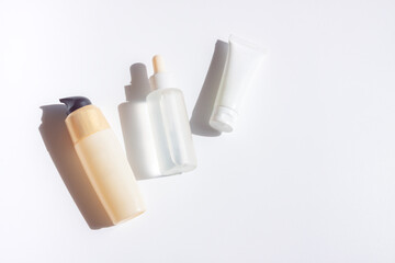 Cosmetic bottles with shadow on white wall background	