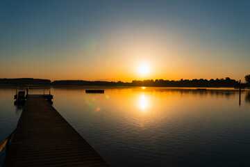 Obraz premium calm sunrise with a jetty, complete blue sky and no clouds, lens flares