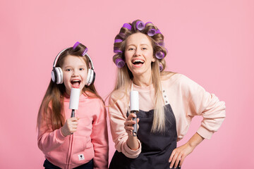 Two beautiful women mother and daughter sing their favorite songs into pretend microphone, fool...