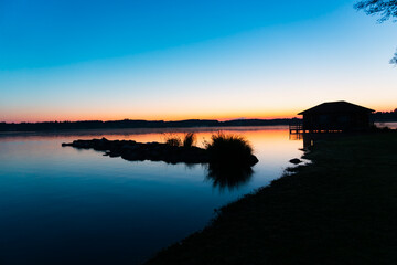 red, orange lake sun rise in Rimsting with a stone jetty and a small sea house as silhouettes