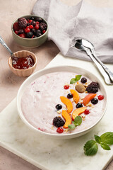 Traditional breakfast semolina porridge - purple creamy pudding with apricot slices, frozen berries, fresh mint, jelly on marble board