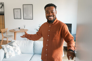 Cheerful Black Guy Opening Door Standing At Home