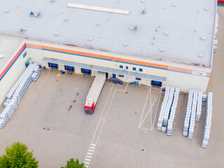 Aerial view of goods warehouse. Logistics center in industrial city zone from above. Aerial view of trucks loading at logistic center