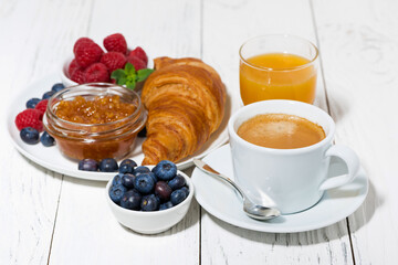 delicious breakfast with croissant and fresh berries on white wooden  table, top view