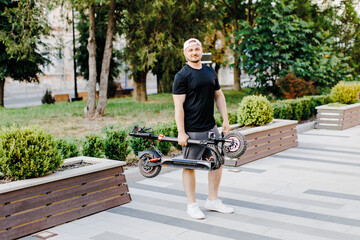 Man carry electric scooter in a folded position. Male wear stylish clothes and hold electric...