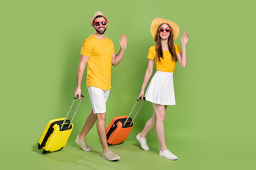 Full length portrait of two people walking arm palm waving hi bye isolated on green color background © deagreez