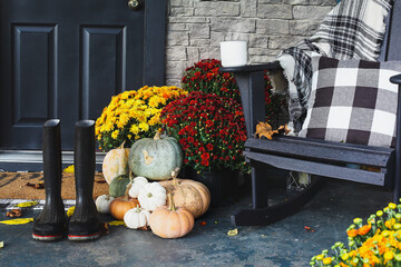 Hot coffee sitting on rocking chair on front porch that has been decorated for autumn with white,...