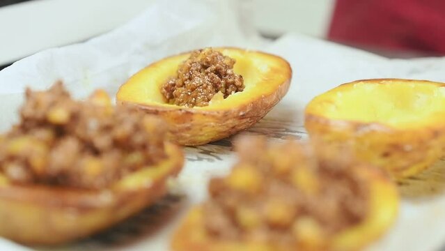 Chef stuffing baked potatoes with ground beef.