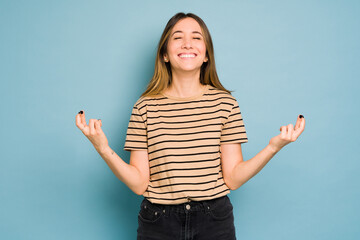 Woman dressed casual with fingers crossed making a wish in a studio