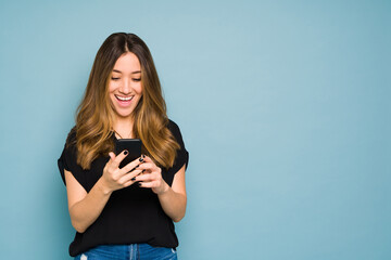 Excited young woman looking at her smartphone in a studio