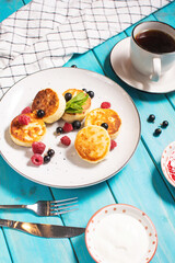 Cottage cheese pancakes, ricotta fritters or syrniki with currant and raspberry. Healthy and delicious breakfast.
