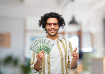 finance, currency and people concept - happy man holding hundreds of euro money banknotes showing...