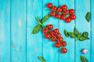 Fresh cherry tomatoes and basil with spices on a blue wooden background . Top view