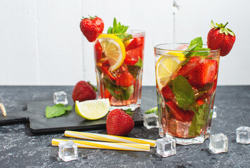 Summer refreshing mojito cocktail with strawberry, mint and lime on a dark stone table