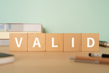 有効・正当のイメージ｜「VALID」と書かれたブロックが置かれたデスク
