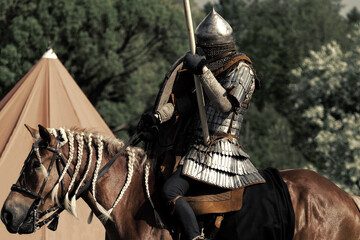 Knight in armor on a horse with a spear. Defender on guard. Brown warhorse with rider.