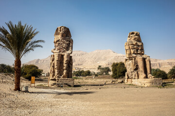 Beautiful daytime view of the Colossi of Memnon. Two large stone figures depicting a seated pharaoh. This is all that remains of the huge memorial temple of Amenhotep III.