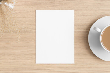 Obraz na płótnie Canvas White invitation card mockup with a dry flower on the wooden table. 5x7 ratio, similar to A6, A5.