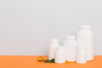 Omega-3 capsules lie in white bottle on a table with green leaves background. Fish oil tablets. Biologically active additives. omega 6, omega 9, vitamin A, E, D, vitamin D3 top view with copy space