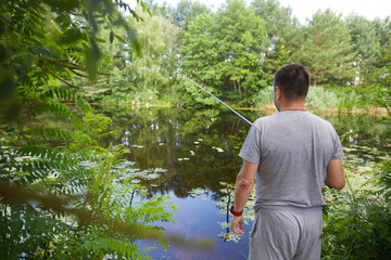 Caucasian adult man fishing on the river with beautiful view of landscape.