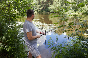 Caucasian adult man fishing on the river with beautiful view of landscape.