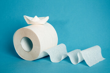 a roll of toilet paper and a paper boat lying on it