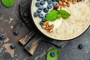 Obraz na płótnie Canvas oatmeal porridge with ripe blueberries for healthy breakfast on rustic wooden board. close up Detox and healthy superfoods bowl concept