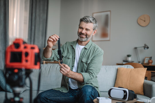 Smiling senior european male blogger records video review on technology and shows smart watch with empty screen - Powered by Adobe