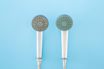 New and old shower heads on light blue table background. Pastel color. Compare two objects with and...