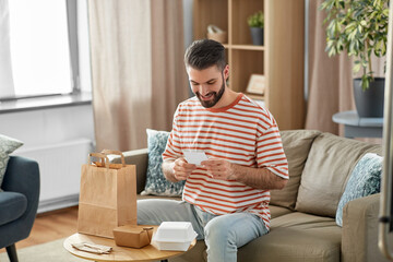 communication, leisure and people concept - happy smiling man with bill checking takeaway food...