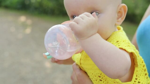 Portrait of a cute drinking little toddler girl. baby drinks from a baby cup.