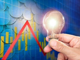 Hand holding a light bulb in front of a graphic. Energy price concept.