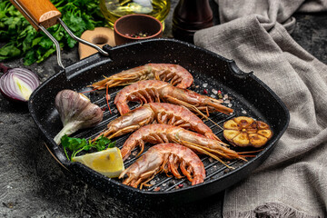 Grilled tiger shrimps with spice, lemon and garlic in a frying pan on a dark background. Prawns fried on a dark background, Seafood appetizer, banner, menu, recipe place for text, top view