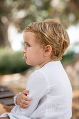 Side view of upset baby girl looking away outdoors.