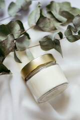 white candle with light background and eucalyptus leaves
