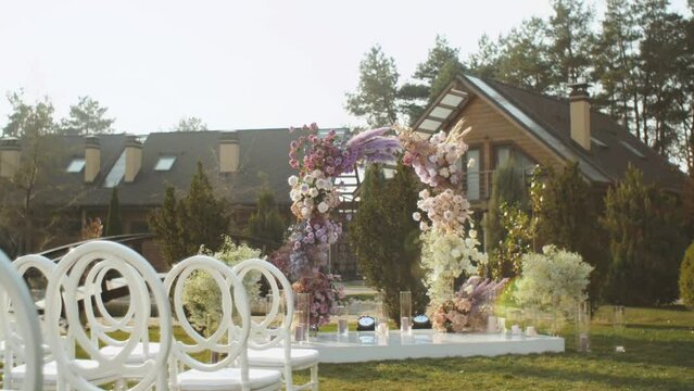 View of Wedding floral decorations of flowers in pastel faded colors slow motion, outside wedding ceremony in park, the sun's rays shine through the arch.