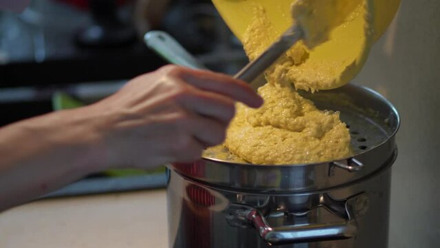 Cooking Bryndzove Halusky - Woman Pour The Batter On Spaetzle Maker With Spatula And Push Through Into The Boiling Water.