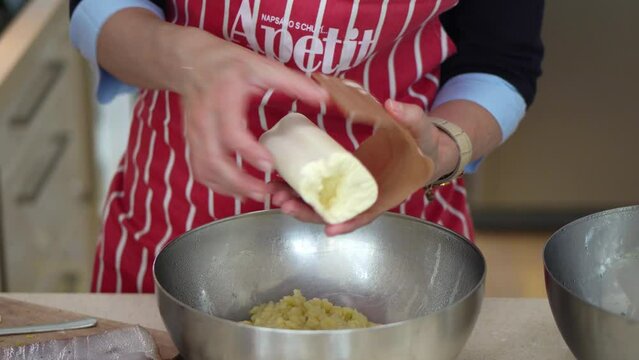 Woman Adds Bryndza (Sheep Cheese) Into Halusky (Potato Dough) In A Mixing Bowl. Bryndzove Halusky. close up