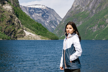 Naklejka premium Young tourist girl in the foreground and behind her the fjord with the high mountains in Gudvangen - Norway