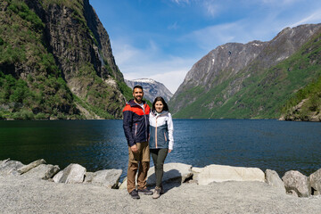 Tourist couple at the foot of the fjord and surrounded by high mountains in Gudvangen - Norway