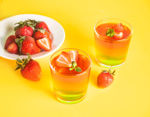 Glasses of tasty summer dessert layered colorful jelly with fresh strawberries