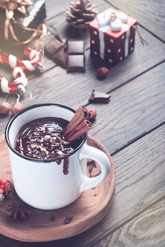 Hot chocolate. Homemade spicy hot chocolate with cinnamon, crushed hazelnut in enamel mug on old wooden background. Toned image. Cozy seasonal holidays.