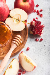 Rosh Hashanah. Pomegranate, apples and honey traditional products for celebration on rustic grey background. Jewish Autumn Rosh Hashana celebration. Jewish holiday Rosh Hashana design. Selective focus