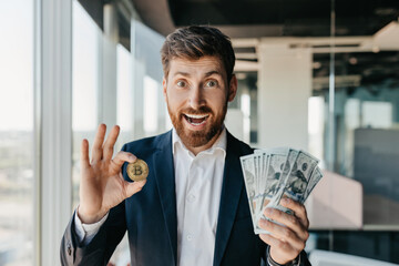Crypto trading. Excited businessman holding golden bitcoin coin and dollar cash banknotes, standing in modern office