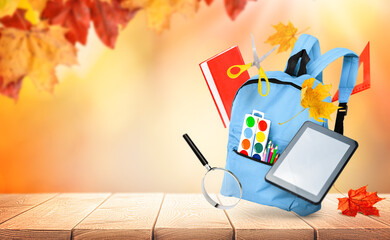 backpack and various school supplies on autumn natural background, back to school